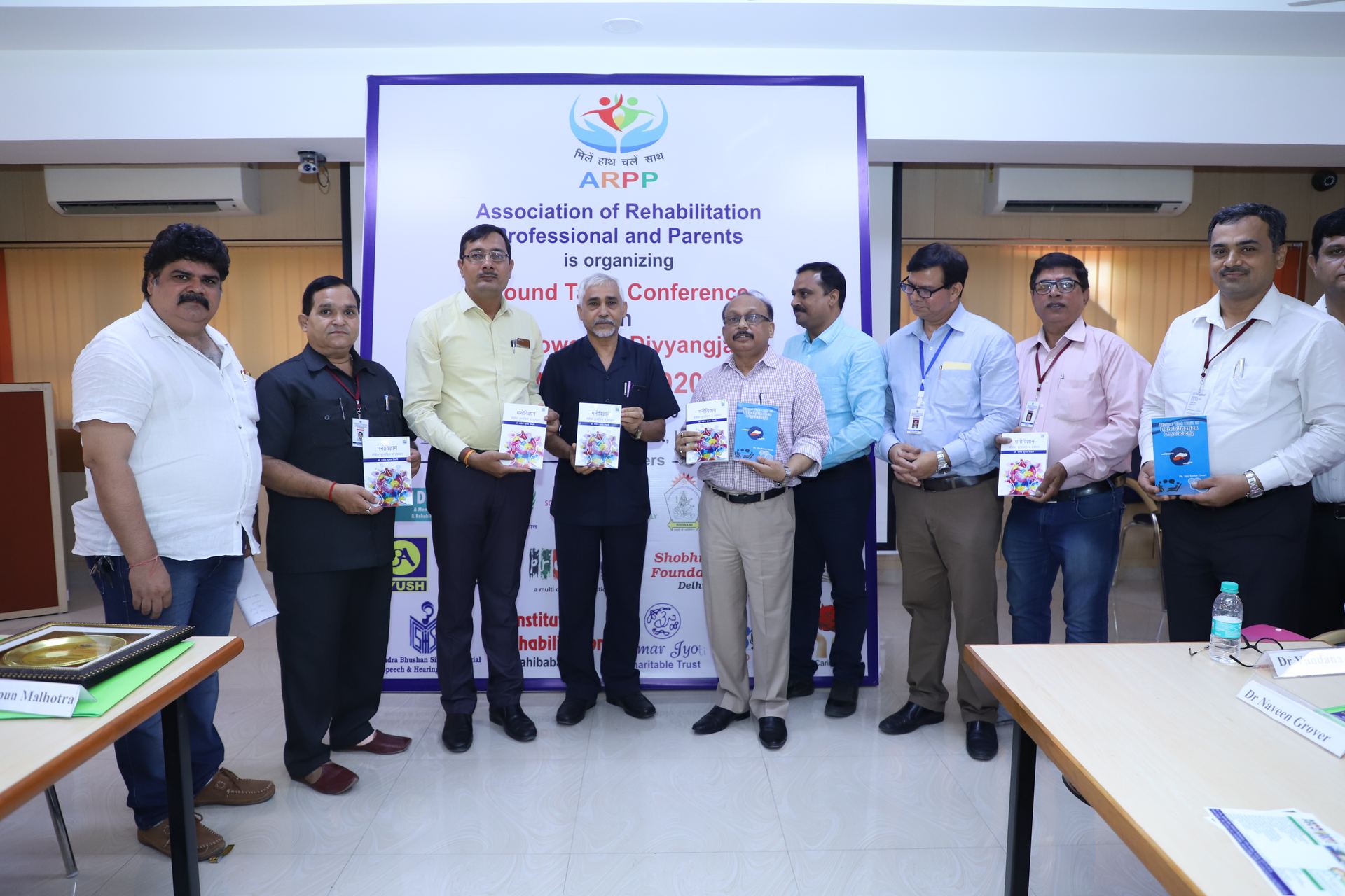 Panel of speakers at ARPP's Round Table Conference on Empowering Divyangjan, each holding a copy of the released book.